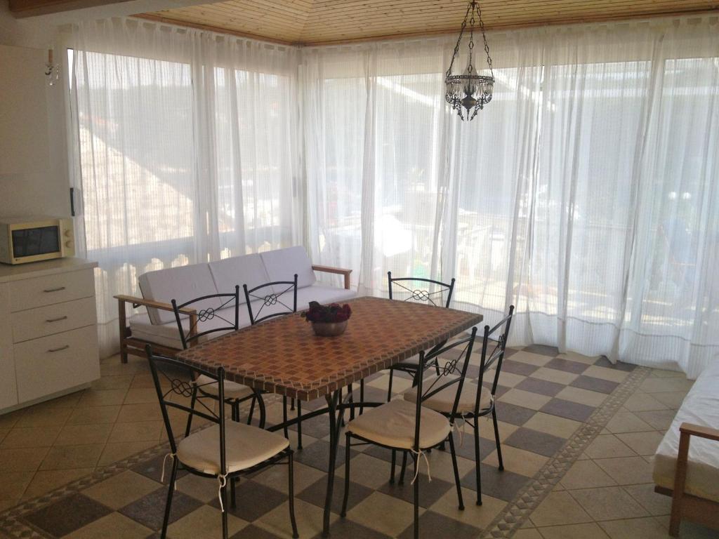ein Esszimmer mit einem Tisch, Stühlen und Fenstern in der Unterkunft Apartments Mediteraneo in Molat