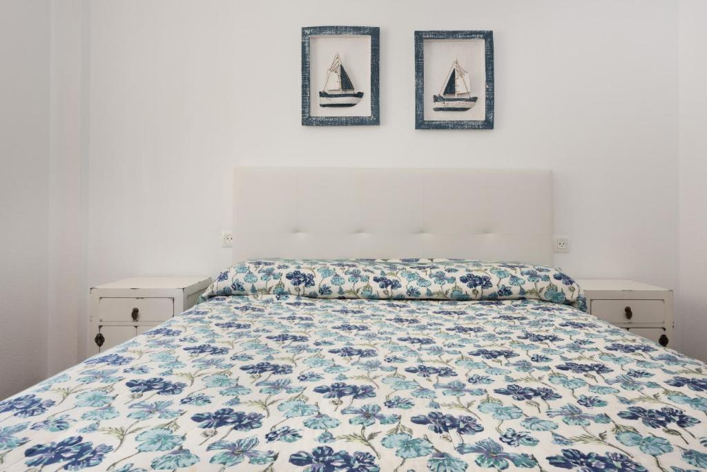 a bed in a bedroom with three pictures on the wall at Apartamento Lance Playa in Tarifa
