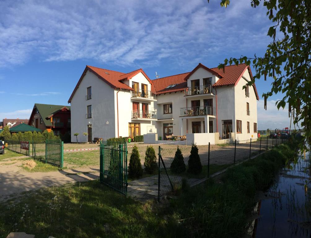 a large white house with a fence in front of it at Pokoje Gościnne Rybitwa in Karwia