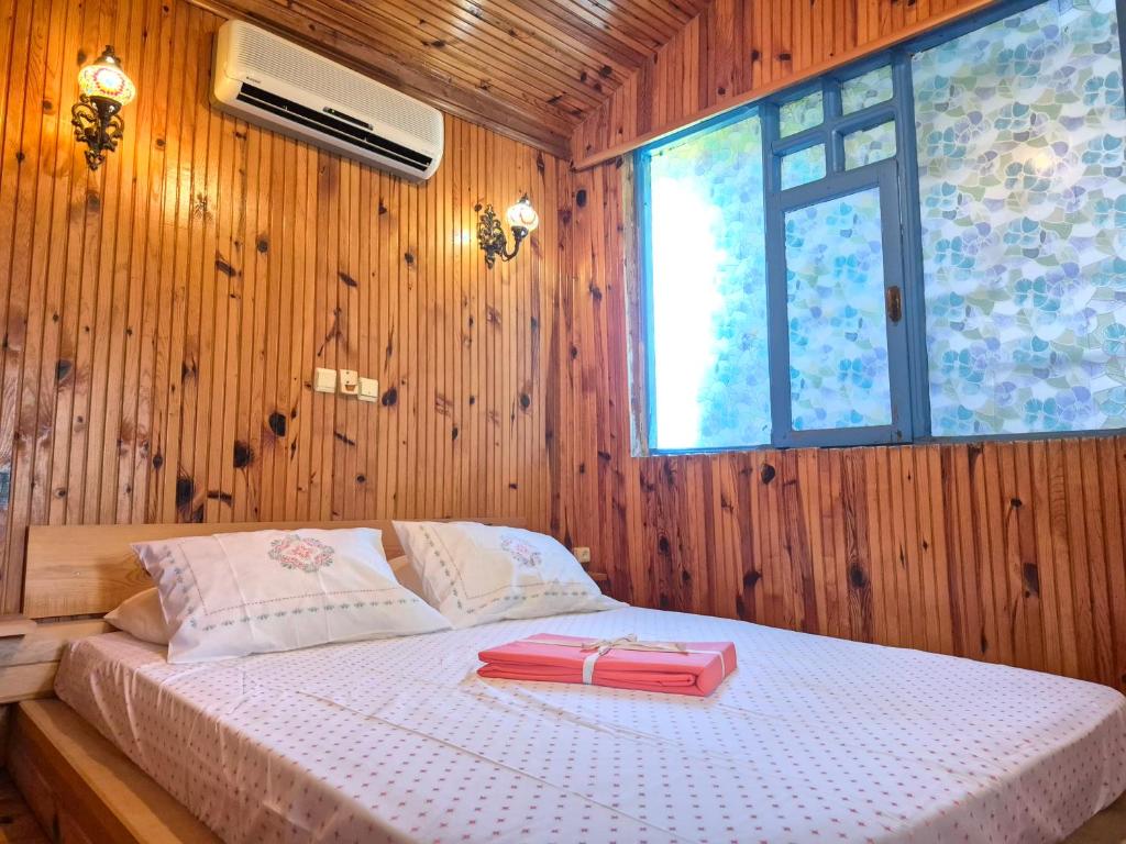 a bedroom with a bed with a pink book on it at Tahtavilla Pansiyon in Cıralı