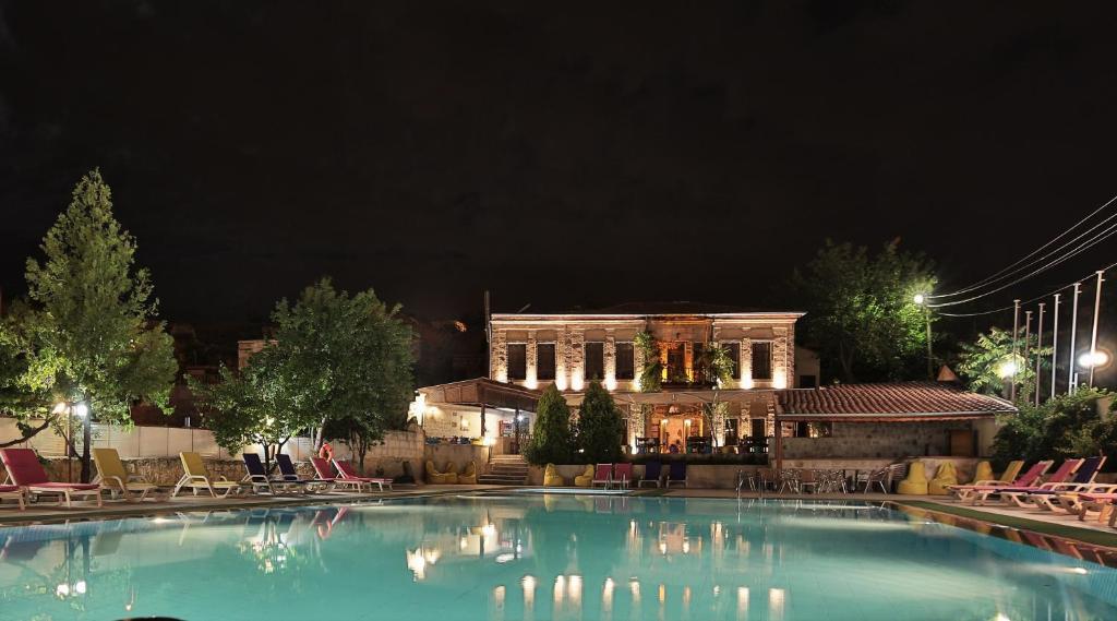 a large swimming pool in front of a building at night at Elif Stone House in Urgup