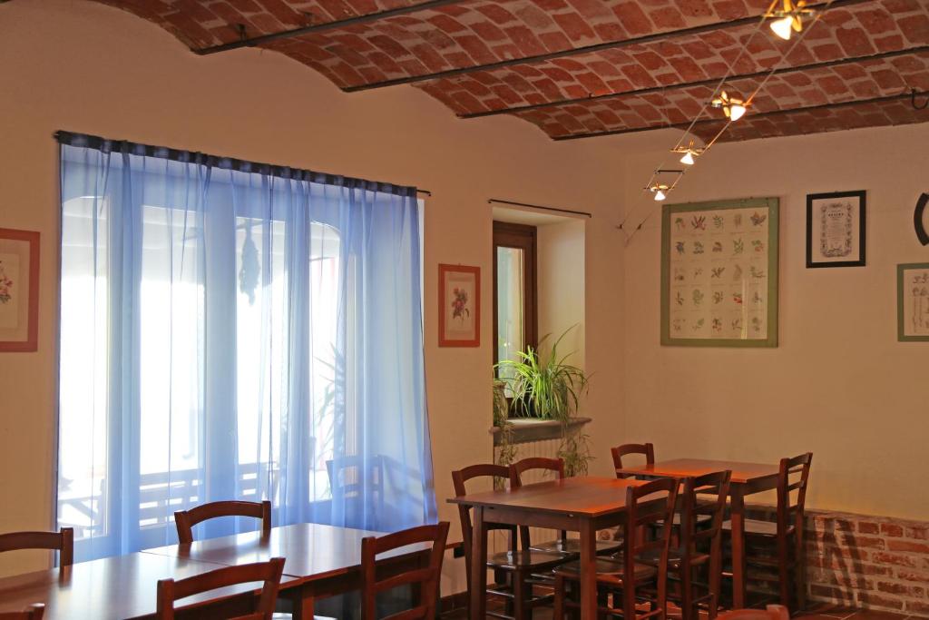 ein Esszimmer mit Tischen, Stühlen und einem Fenster in der Unterkunft La Volpe E L'uva in Cherasco