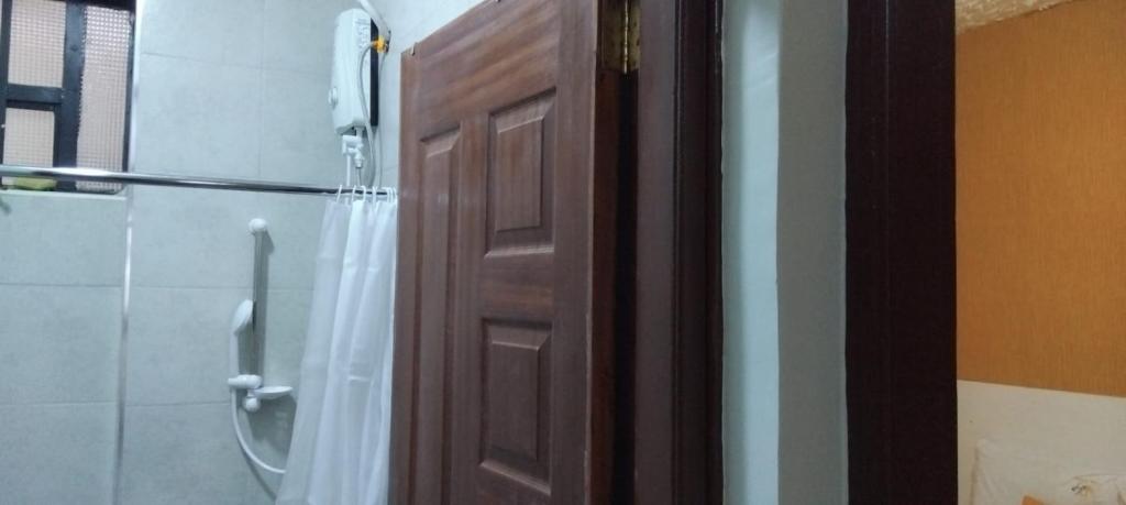 a bathroom with a shower and a wooden door at Yellow Petals Homestays in Nanyuki