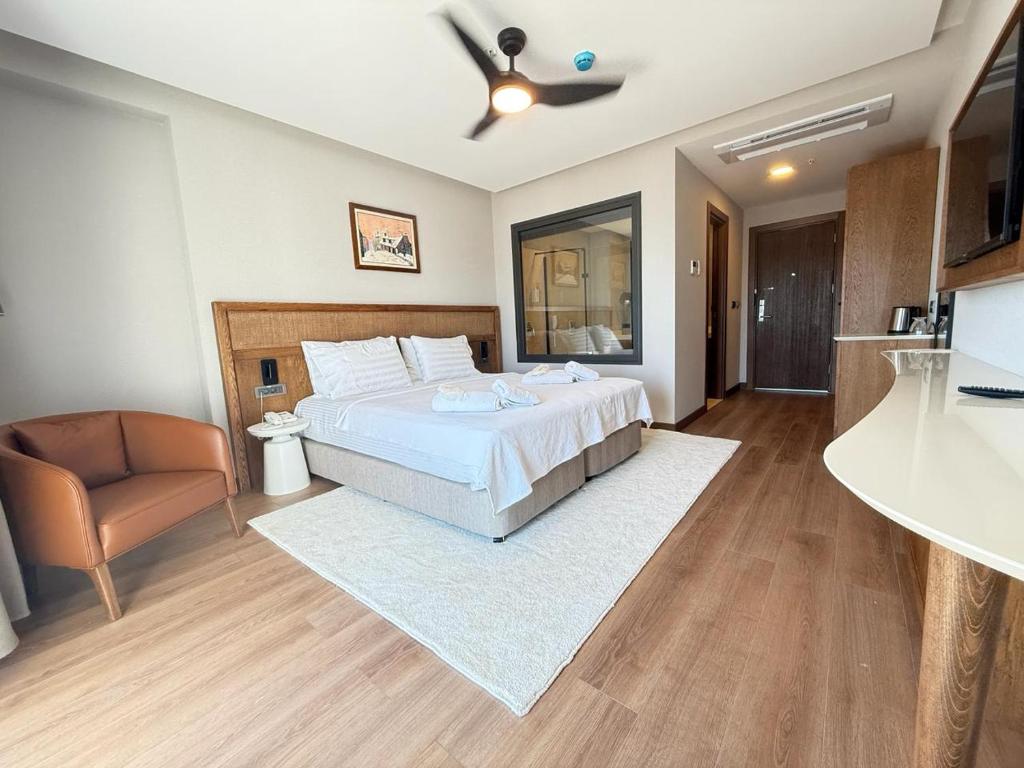 a large bedroom with a bed and a chair at Cunda Kızılca Deluxe Hotel & SPA in Ayvalık