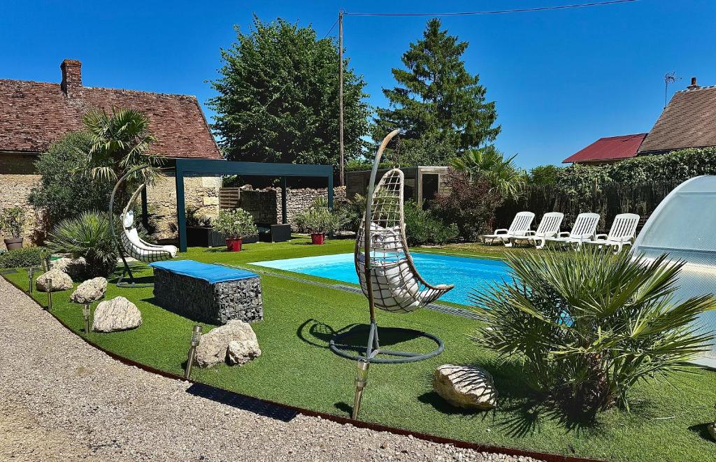 a garden with two swinging chairs and a pool at Gîte La Belle Aventure avec piscine et jacuzzi in Mosnes