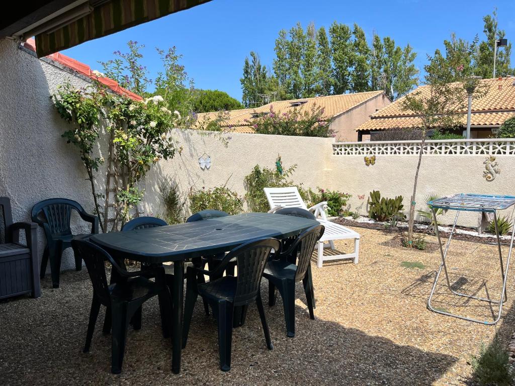 une table noire et des chaises dans une cour dans l'établissement Jolie maison d'angle, pour 4 couchages, terrasse, résidence piscine commune à 400m plage de PORTIRAGNES PLAGE LRJP134, à Portiragnes