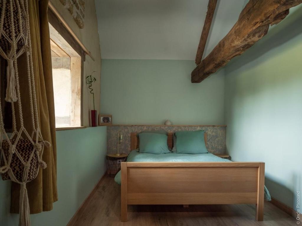 a bedroom with a bed with blue pillows and a window at Ti Ana Chambre Bohème in Évran