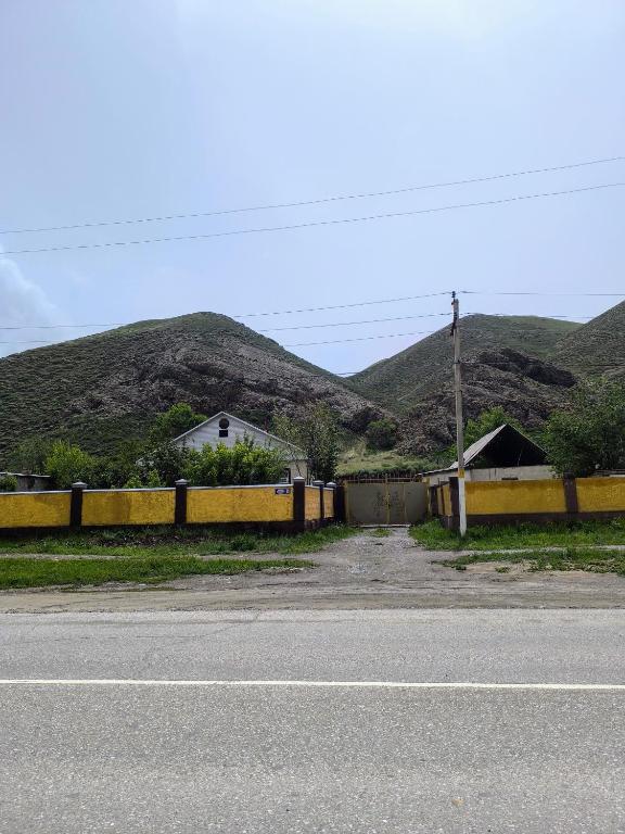 a house with a fence and mountains in the background at Naryn Cozy House in Naryn