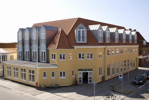 ein großes gelbes Gebäude mit braunem Dach in der Unterkunft Seaside Hotel Thyborøn in Thyborøn