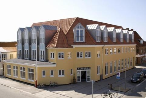 Seaside Hotel Thyborøn في Thyborøn: مبنى أصفر كبير بسقف بني