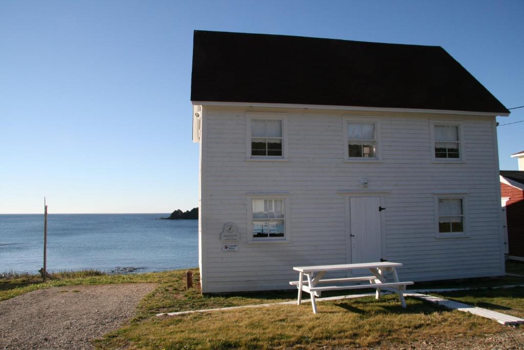 a white house with a bench in front of it at The Old Salt Box Co - Gertie's Place in Twillingate