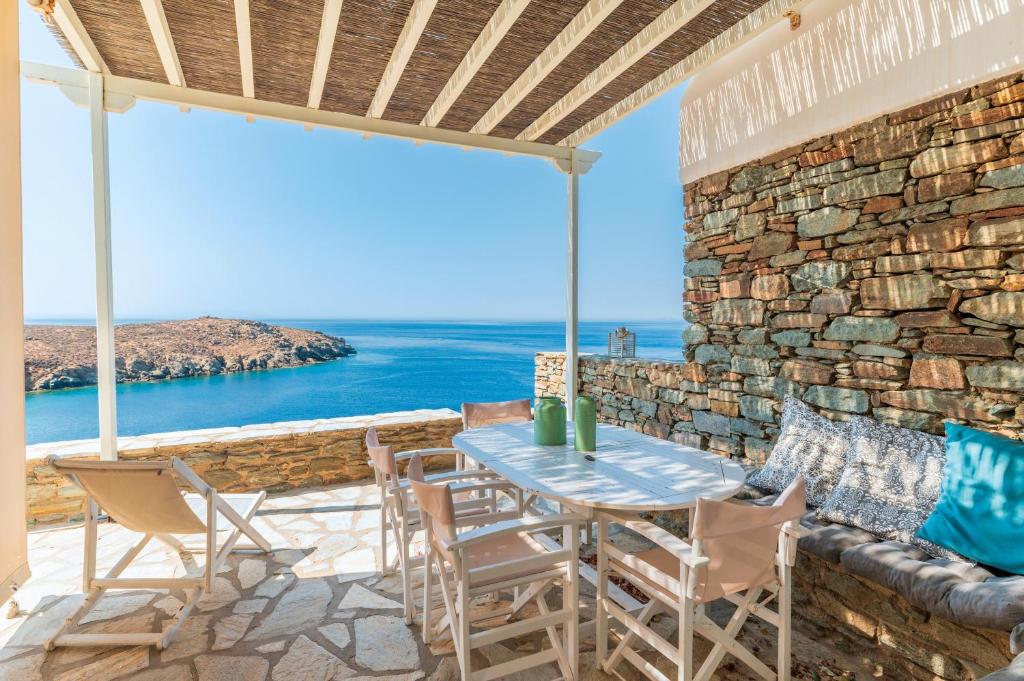 a patio with a table and chairs and the ocean at Sun Blooming Villa In Tinos Island in Agios Romanos