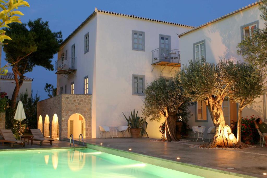 a house with a swimming pool in front of a building at Orloff Resort in Spetses