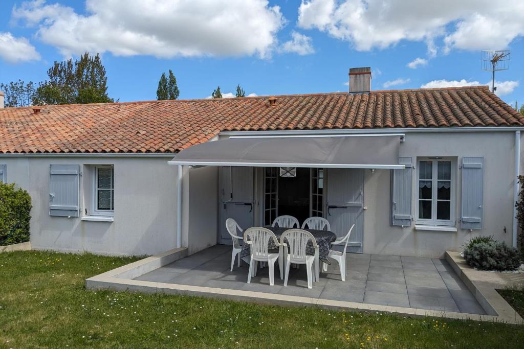 Cette maison blanche dispose d'une terrasse avec des chaises et une table. dans l'établissement Haven of peace 2 steps from the sea, à La Tranche-sur-Mer