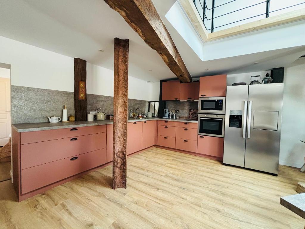 a kitchen with pink cabinets and stainless steel appliances at Le Gîte Eiffel Les Gîtes de l'Atelier in Gaudonville