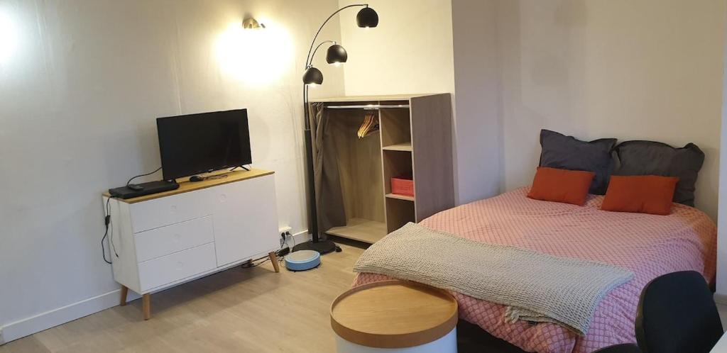 a bedroom with a bed and a tv on a dresser at apartment building features laundry facilities in Beauzelle