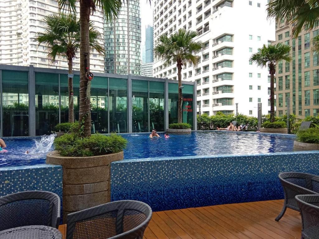 a pool with palm trees and people in a building at Vortex Suites KLCC by Comfy Stay in Kuala Lumpur