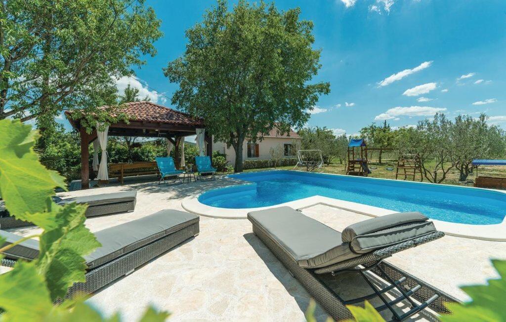 a swimming pool with chairs and a gazebo at House Marin in Drniš