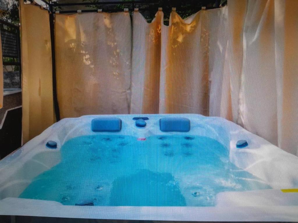 a jacuzzi tub with blue water in front of a curtain at Apartments Roza in Dramalj