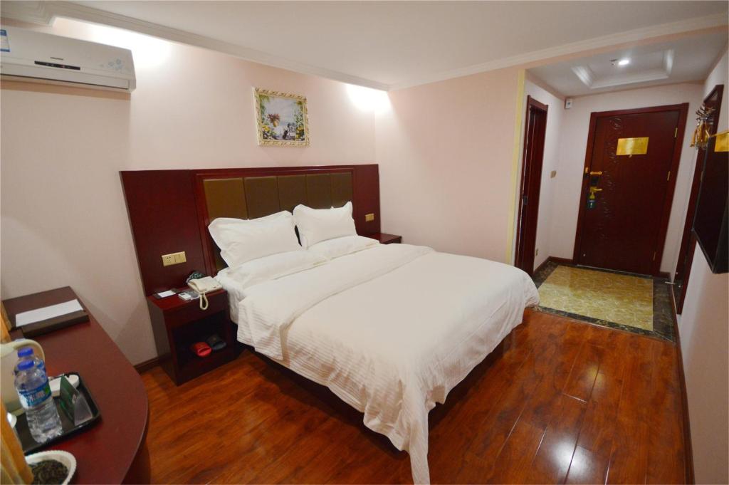 una camera da letto con un grande letto bianco e pavimenti in legno di GreenTree Inn Nanning Xiuxiang Branch a Nanning