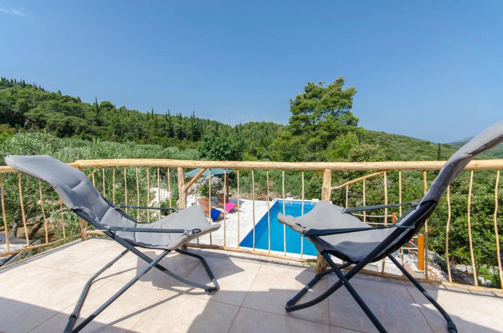 a pair of chairs on a balcony with a pool at House Nikica in Korčula