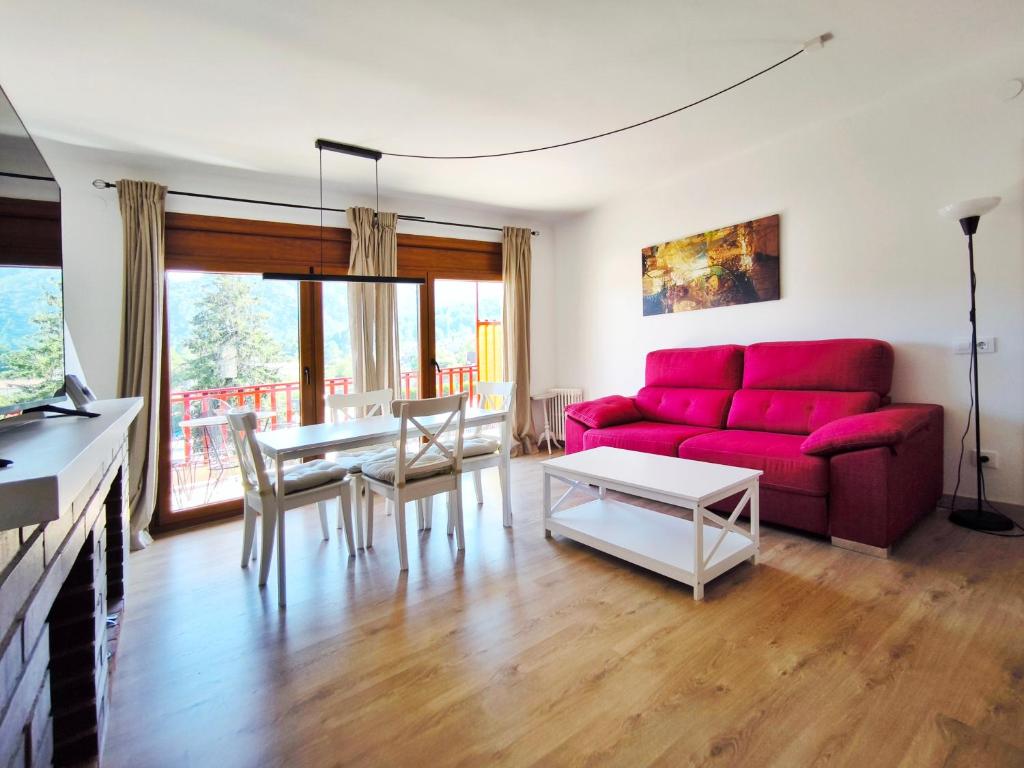 a living room with a red couch and a table at Vall de Lord, terraza con vistas a la montaña in Sant Llorenc de Morunys