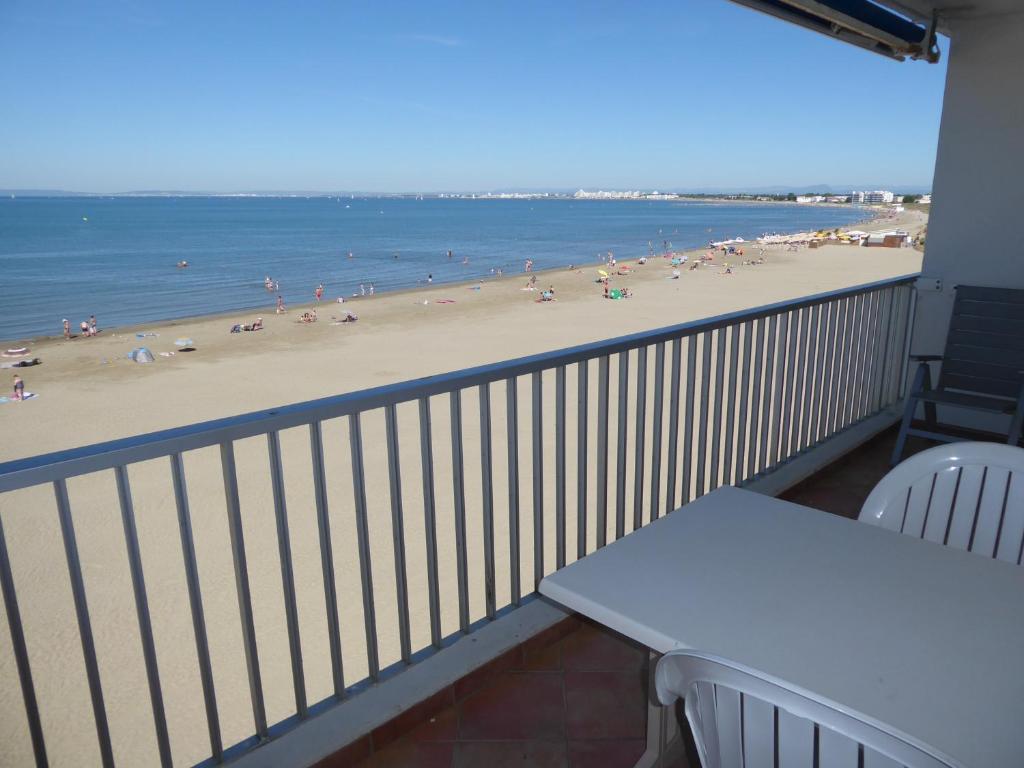 a balcony with a table and chairs and a beach at Appartement 1 chambre terrasse vue sur mer in Le Grau-du-Roi