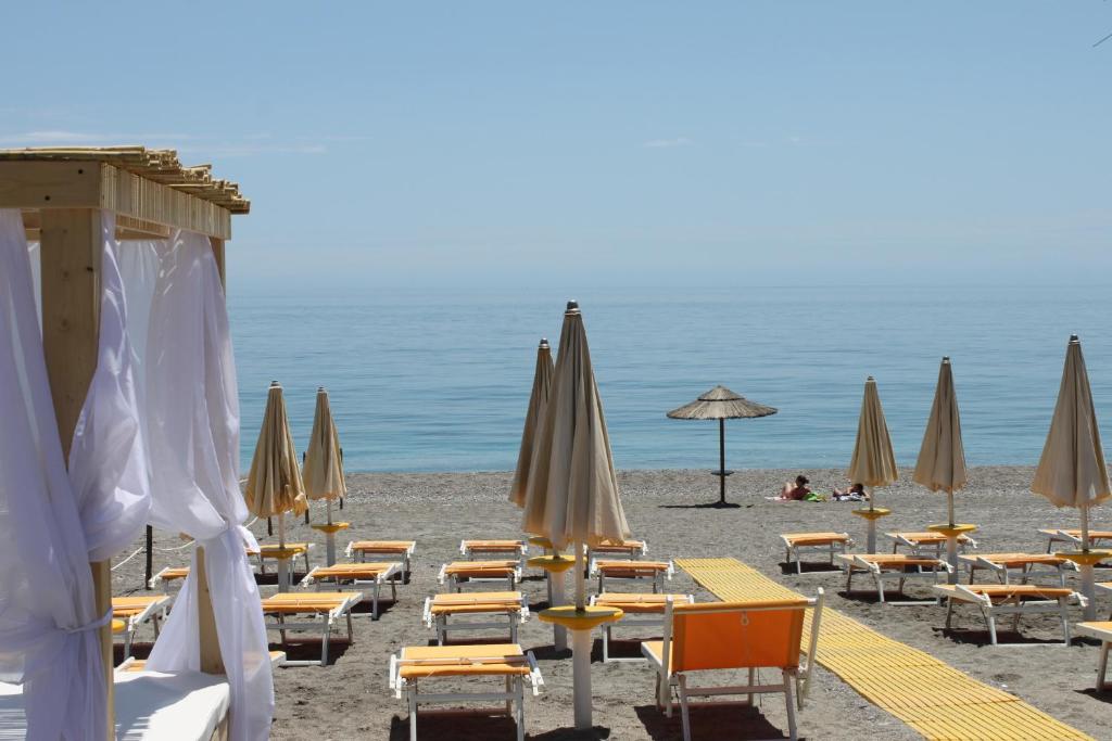 a beach with tables and chairs and umbrellas at La Terrazza sul Mare in Letojanni