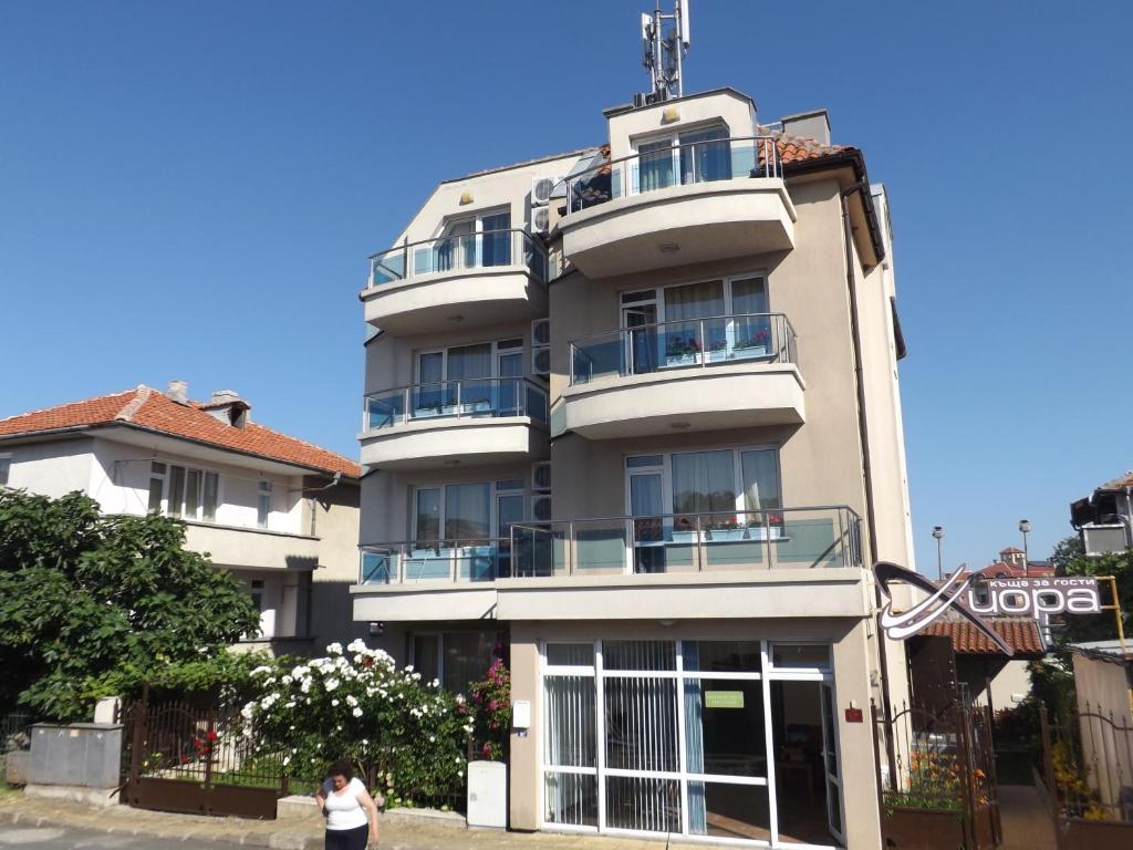 a woman standing in front of a tall building at Guest House Hiora in Ahtopol
