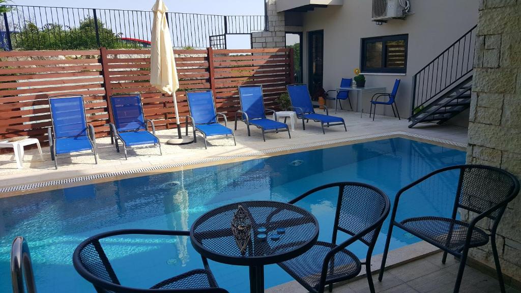 a patio with chairs and a table next to a pool at Ornella Beach Resort & Villas in Syvota