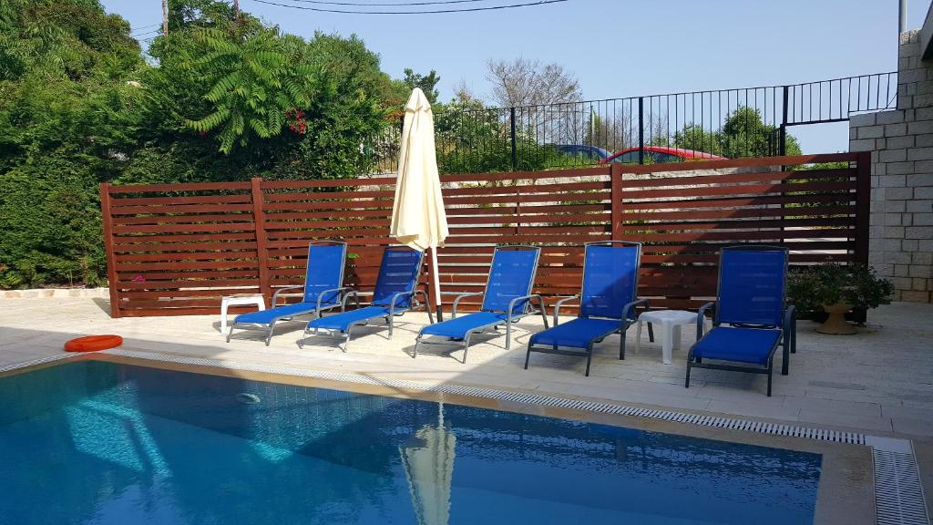 a group of chairs and an umbrella next to a pool at Ornella Beach Resort & Villas in Syvota