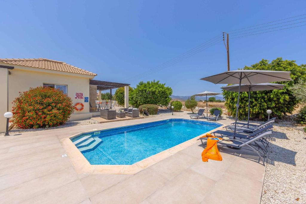 a swimming pool with two chairs and an umbrella at Villa Orange Tree in Lachi