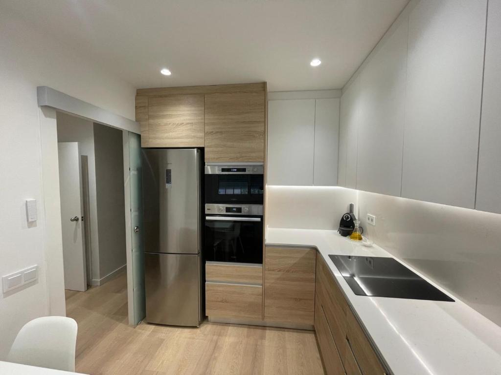Una cocina con frigorífico de acero inoxidable y fregadero. en Habitación Winahost Sant Cugat, en Sant Cugat del Vallès