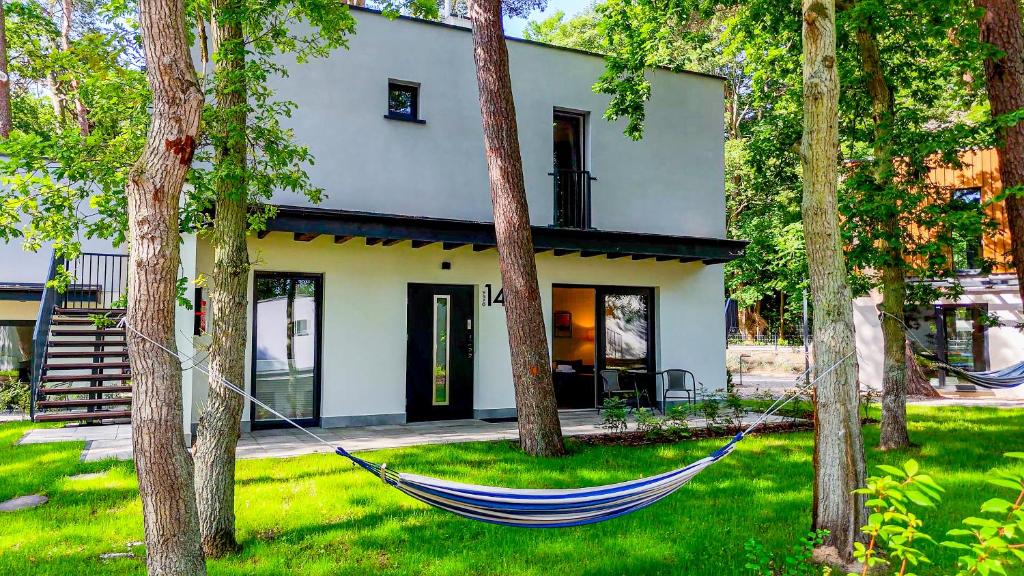 a hammock in front of a house with trees at Baltic Forest in Kołobrzeg
