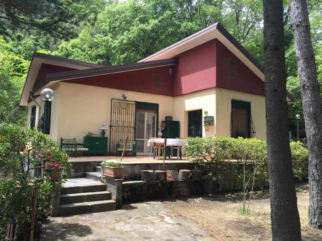 a house with a woman sitting at a table in front of it at Chalet Serra Pizzuta in Nicolosi