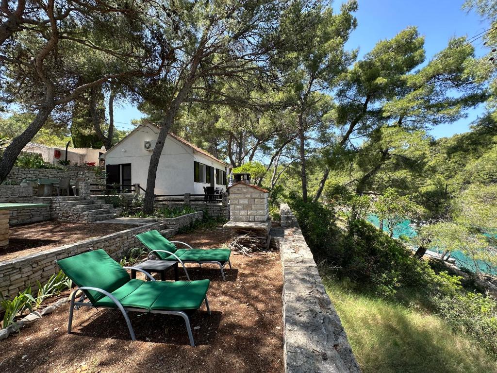 two chairs and a table in front of a house at House Neli in Srednje Selo na Šolti