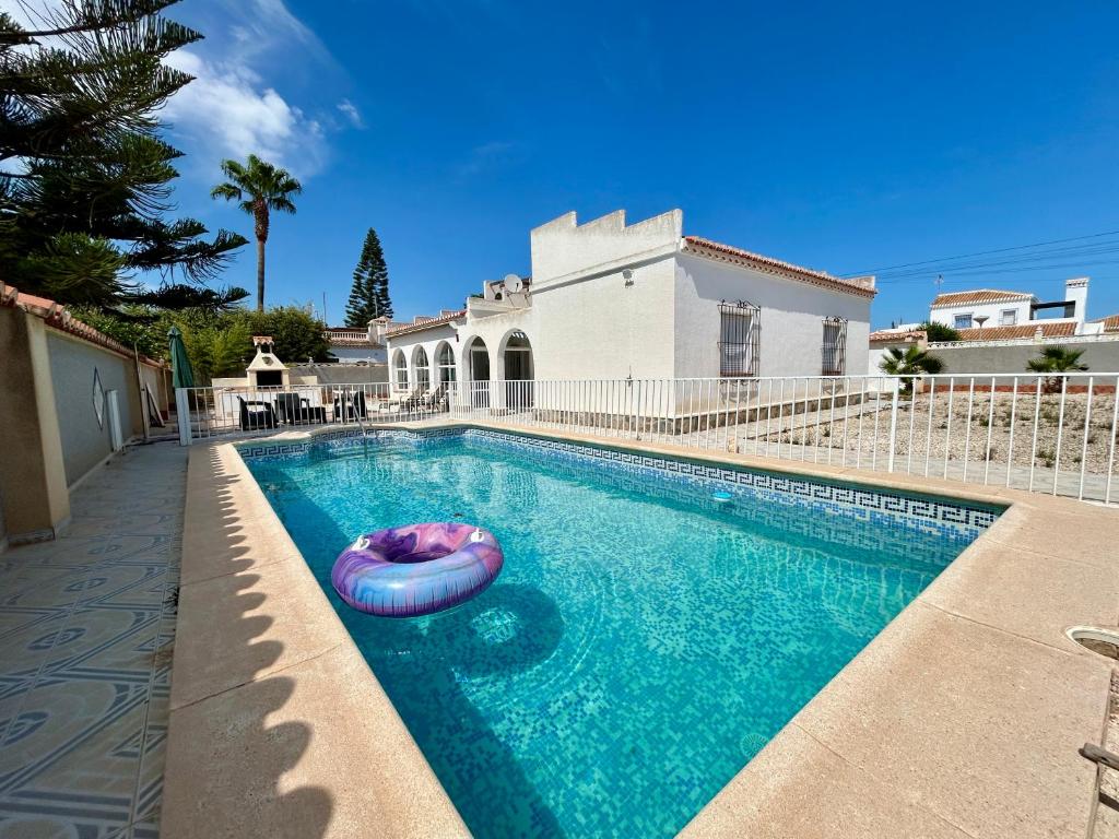 a swimming pool with an inflatable raft in front of a house at Villa with Pool, Chill-Out & BBQ in Torrevieja