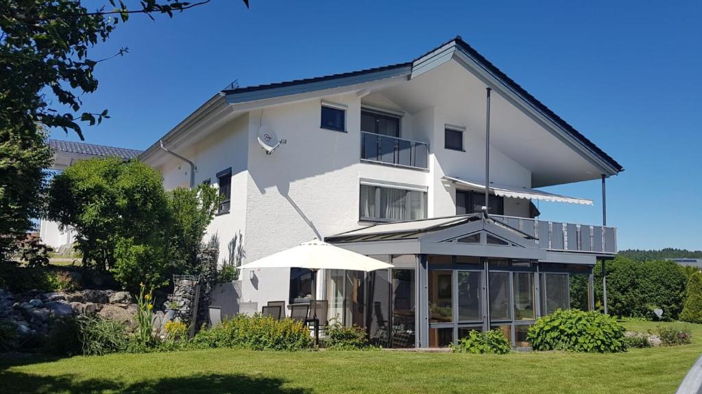 ein weißes Gebäude mit einem Schirm davor in der Unterkunft Ferienwohnungen Familie Hofer in Argenbühl