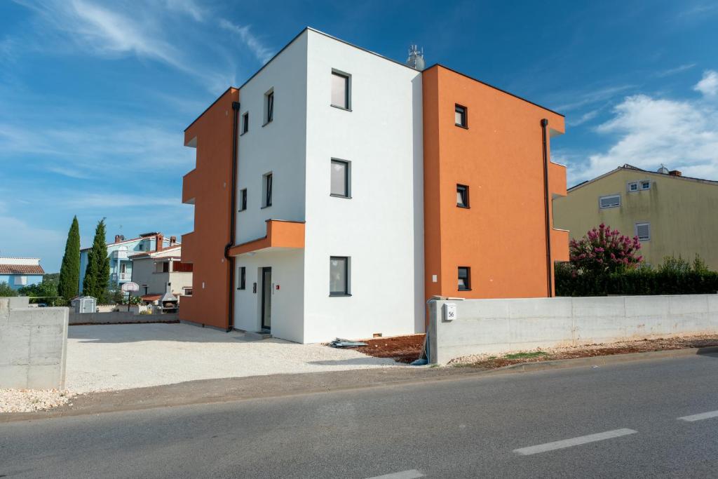a white and orange building on the side of a street at Apartmani Iman in Medulin