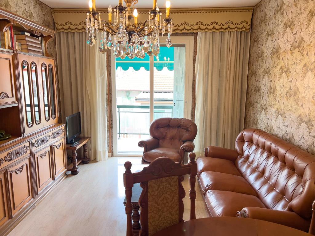 een woonkamer met een leren bank en een kroonluchter bij Casa Francy - Taggia in Arma di Taggia