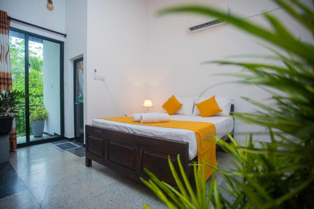 a bedroom with a bed with yellow pillows at Vibe green villa in Unawatuna