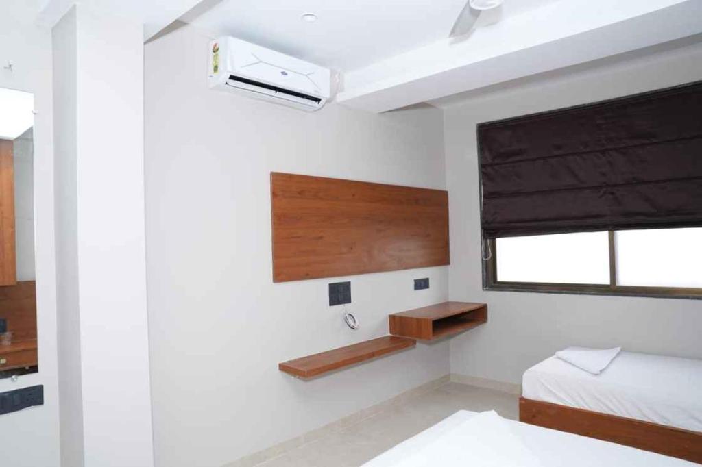 a white bedroom with a bed and a window at Hotel Yashraj Regency in Sangamner