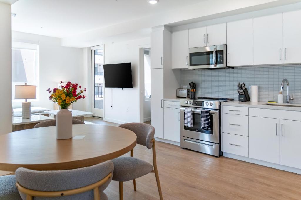 a kitchen with white cabinets and a table and chairs at Luxury 2 Bedroom 2 Bathroom Residence With Fitness and Outdoor Pool in Los Angeles
