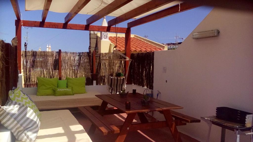 a patio with a table and green pillows at Casa Verão Azul in Monte Gordo