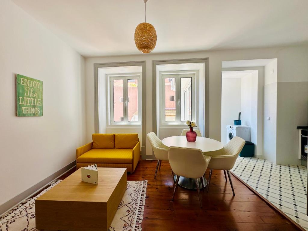 a living room with a table and a yellow couch at Nassima Lisboa in Lisbon