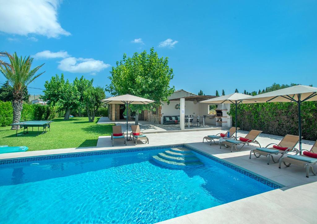 ein Schwimmbad mit Stühlen und Sonnenschirmen in der Unterkunft Owl Booking Villa Divina - Luxury Retreat in Pollença