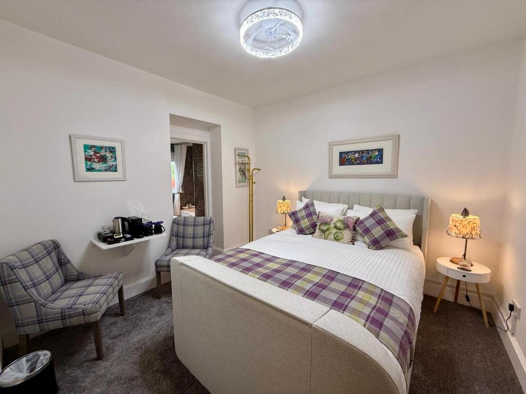 a bedroom with a large bed and a chair at Carron Cottage in Inverness