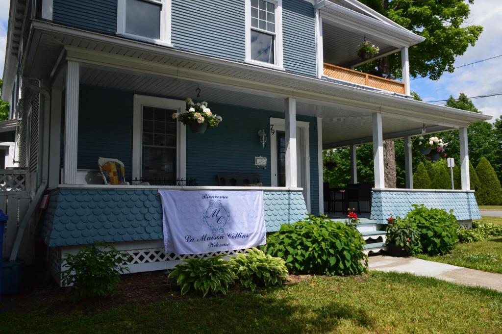 ein blaues Haus mit einem Banner auf der Veranda in der Unterkunft La Maison Collins B&B in Granby