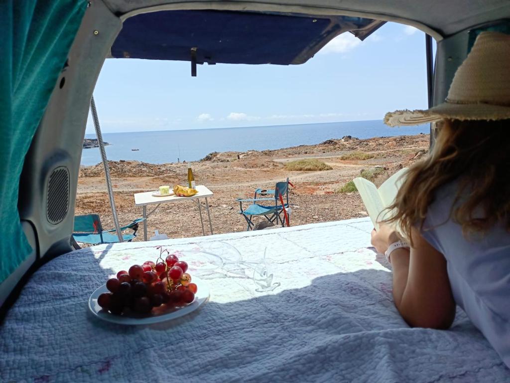 Una mujer sentada en una tienda de campaña con un plato de fruta. en Discovery Canarias III, en San Miguel de Abona