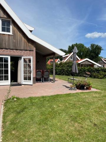 a house with two chairs and an umbrella in the yard at Estate the Lageveld 94 in Hoge-Hexel